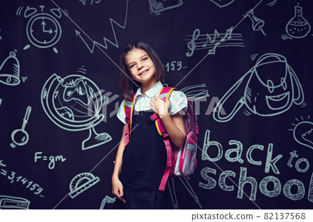 Cute smiling caucasian schoolgirl preparing to go to school with backpack. Back to school concept Cute smiling caucasian schoolgirl preparing to go to school with backpack. Back to school concept 82137568