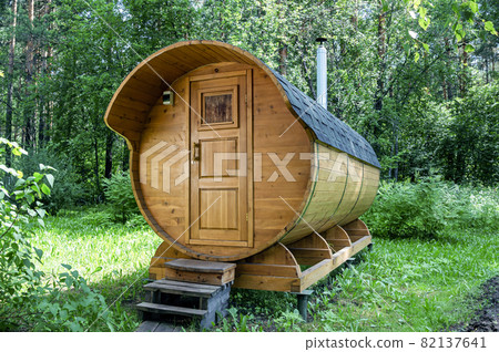 Round wooden barrel bath stands in the forest on a sunny summer day 82137641