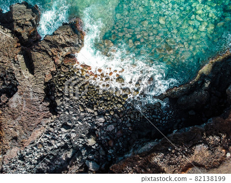 Aerial view of rocks and sea waves in a volcanic landscape with lava Aerial view of rocks and sea waves in a volcanic landscape with lava 82138199