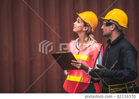 Industrial worker works with co-worker at overseas shipping container yard 82138370
