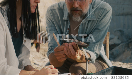 Crop archaeologist measuring golden necklace 82138685