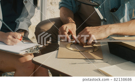 Crop archaeologist measuring golden necklace 82138686