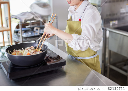 A young woman in an apron cooking in the kitchen A young woman in an apron cooking in the kitchen 82139731
