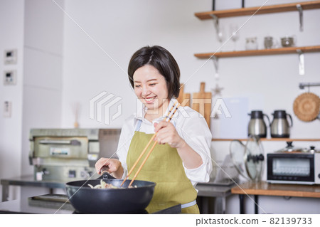 一個穿著圍裙在廚房做飯的年輕女人 一個穿著圍裙在廚房做飯的年輕女人 82139733