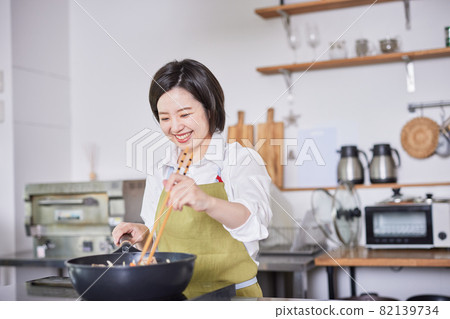 一個穿著圍裙在廚房做飯的年輕女人 一個穿著圍裙在廚房做飯的年輕女人 82139734