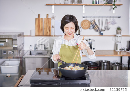 一個穿著圍裙在廚房裡做咖哩的年輕女人 一個穿著圍裙在廚房裡做咖哩的年輕女人 82139735
