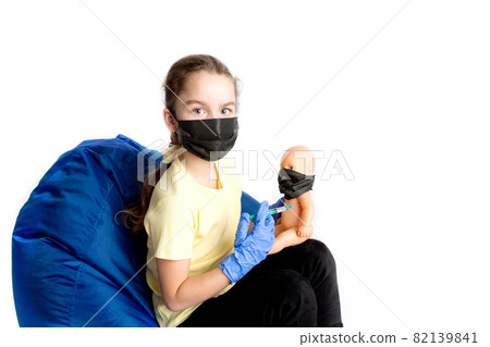 The girl plays a doctor with a doll. The reality of the coronavirus in the lives of children. Injection against covid19. The girl plays a doctor with a doll. The reality of the coronavirus in the lives of children. Injection against covid19. 82139841