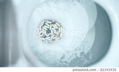 Flushing medical capsules into the toilet. Harmful drug concept Flushing medical capsules into the toilet. Harmful drug concept 82141410
