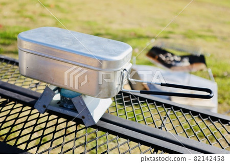 Cook rice with an aluminum mess tin in front of a bonfire 82142458