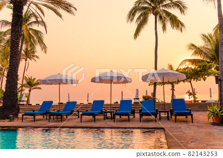 palm tree with umbrella chair pool in luxury hotel resort at sunrise times 82143253