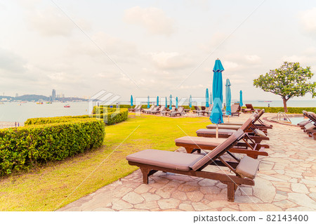 chair pool or bed pool and umbrella around swimming pool with sea beach background 82143400