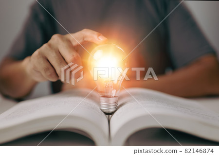 Idea of learning education knowledge online class or e-learning at home. Glowing light bulb and book or text book. Idea of learning education knowledge online class or e-learning at home. Glowing light bulb and book or text book. 82146874