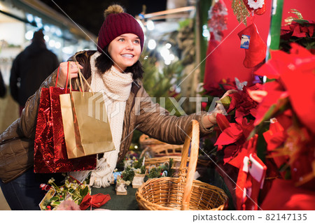 Girl staying with floral composition at Christmas fair Girl staying with floral composition at Christmas fair 82147135