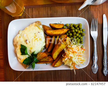 Veal Orloff with potato wedges, green peas and cabbage salad Veal Orloff with potato wedges, green peas and cabbage salad 82147457