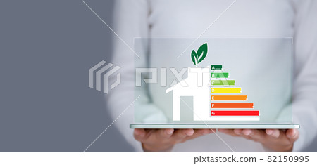 Energy efficiency and green energy concept, woman hand holding tablet and looking at house efficiency rating. Energy efficiency and green energy concept, woman hand holding tablet and looking at house efficiency rating. 82150995