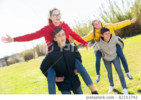 Happy teenage boys piggybacking girls 82151742
