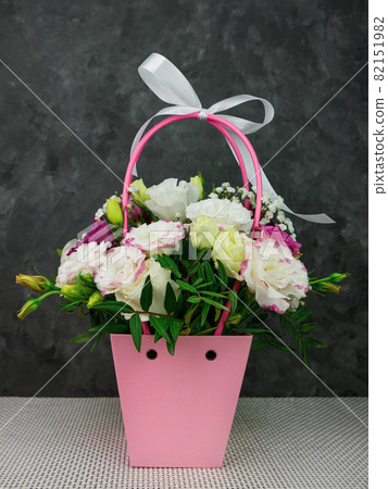 Beautiful white Eustoma Gypsophila flowers bouquet in pink pastel basket dark background. Floral gift blooming wallpaper 82151982