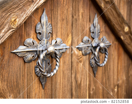 Door handles on a wooden door in the form of forged bronze rings, close-up. Ancient Door handles on a wooden door in the form of forged bronze rings, close-up. Ancient 82152858
