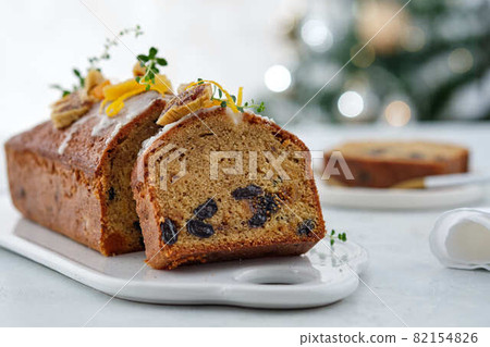 Beautiful delicious homemade Christmas dried fruit cake on grey table with decorating items for celebrating festive season. Beautiful delicious homemade Christmas dried fruit cake on grey table with decorating items for celebrating festive season. 82154826