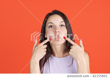Cropped portrait of beautiful young woman making faces isolated over red studio background 82155601