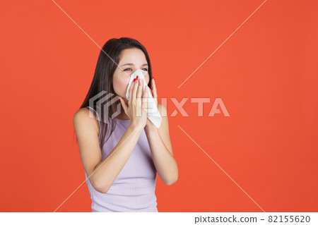 One female model isolated over red studi background. Sneezing 82155620