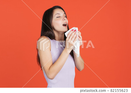 One female model isolated over red studi background. Sneezing 82155623
