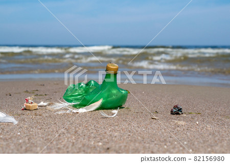 Garbage on the beach. Plastic on the beach. Pollution of the coast with plastic bottles. Green empty bottle. 82156980