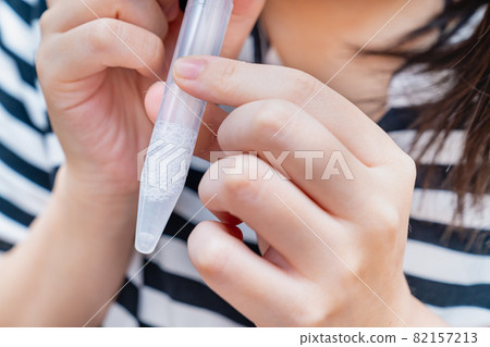 A photo of a woman collecting saliva at home using a PCR test kit. Image of PCR test. 82157213