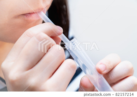 一名婦女在家中使用 PCR 檢測試劑盒收集唾液的照片。 PCR 測試的圖像。 82157214