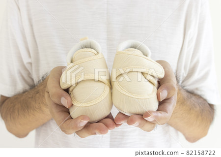 Male hand holding baby shoes Male hand holding baby shoes 82158722