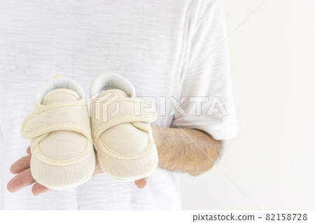 Male hand holding baby shoes 82158728
