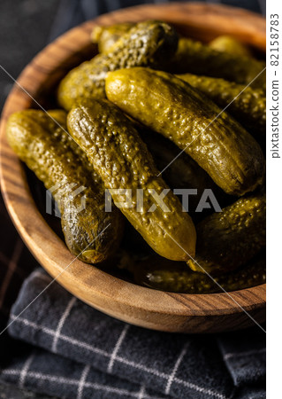 Small pickles. Marinated pickled cucumbers in wooden bowl. 82158783
