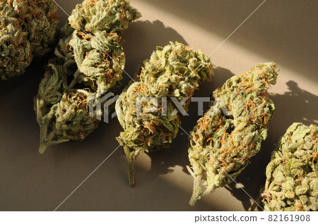Marijuana buds closeup, come in from the cold concept. Medicinal cannabis flowering on brown background. 82161908