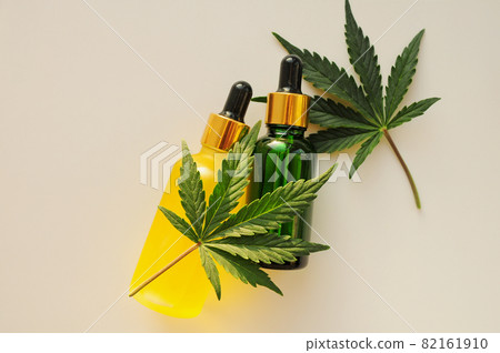 Cannabis leaves, cbd oil. Marihuana extract in cosmetology. Flat lay, light background. Cannabis leaves, cbd oil. Marihuana extract in cosmetology. Flat lay, light background. 82161910