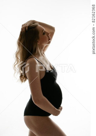 pregnant woman stroking her belly on white background. Copy space. The concept of healthy digestion, lifestyle, IVF 82162368