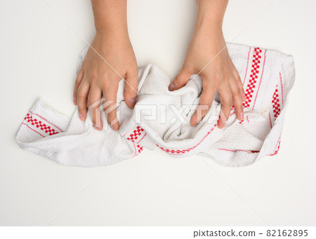 female hand holding a white kitchen towel on a white table, top view female hand holding a white kitchen towel on a white table, top view 82162895