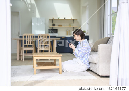 A woman looking at her smartphone in the living room A woman looking at her smartphone in the living room 82163177