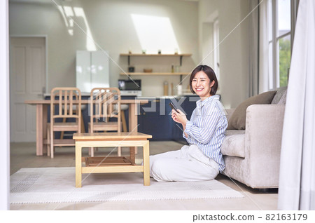 A woman looking at her smartphone in the living room A woman looking at her smartphone in the living room 82163179