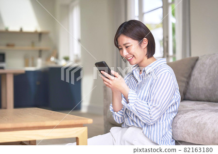 A woman looking at her smartphone in the living room A woman looking at her smartphone in the living room 82163180