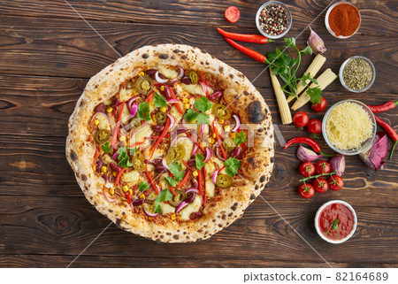 Tradition homemade spicy mexican pizza with chili, beef, onion, jalapeno pepper and ingredients top view on wooden table. Cooking at home concept 82164689