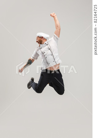 One Caucasian bearded man, chef in uniform jumping high isolated on white background. Concept of job, occupation, humor. 82164725