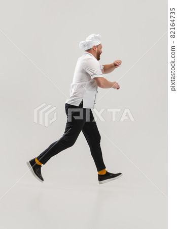 Portrait of cook, chef man in uniform running to kitchen isolated on white background. Concept of job, occupation, humor. 82164735