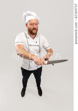 High angle view of hadsome bearded man, cook, male chef in white uniform having fun isolated on white background. Concept of job, occupation, humor. High angle view of hadsome bearded man, cook, male chef in white uniform having fun isolated on white background. Concept of job, occupation, humor. 82164737