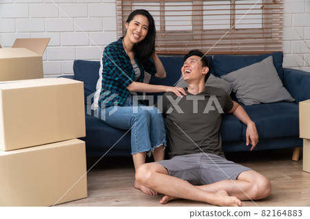 Happy young Asian couple sitting on the sofa for rest after moving to a new house on the first day. Concept of starting a new life for a newly married couple. 82164883
