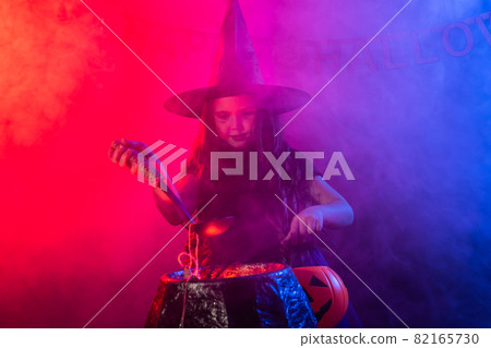 Little witch child cooking potion in the cauldron on Halloween. 82165730