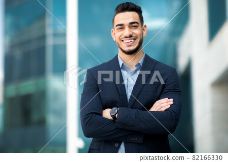 Wealthy middle-eastern businessman posing next to office building Wealthy middle-eastern businessman posing next to office building 82166330