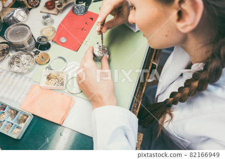 Woman watchmaker working diligently on repairing a watch 82166949