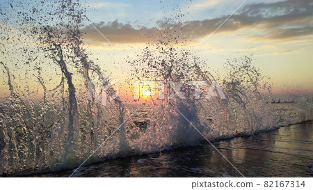 Splashing high wave on sea coast at sunset Splashing high wave on sea coast at sunset 82167314