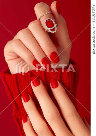 Female hands with manicure in sweater. Red matt nail design 82167378