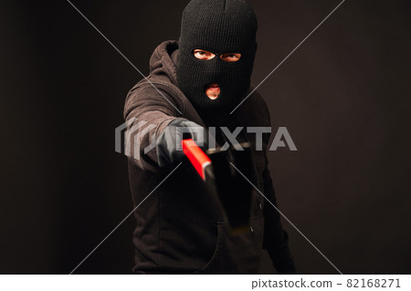 Burglar holding metallic crowbar on black background Burglar holding metallic crowbar on black background 82168271